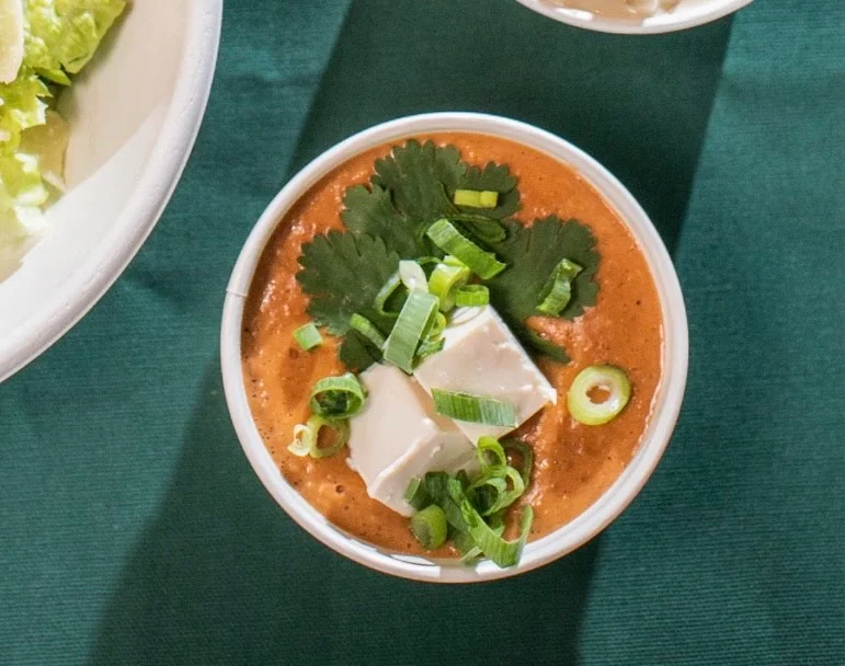 A bowl of soup with tofu and green onionsAI-generated content may be incorrect.