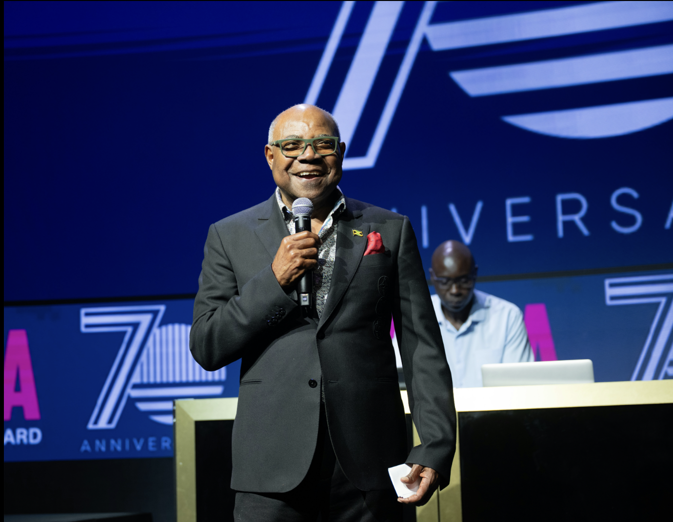 A person in a suit holding a microphoneAI-generated content may be incorrect.